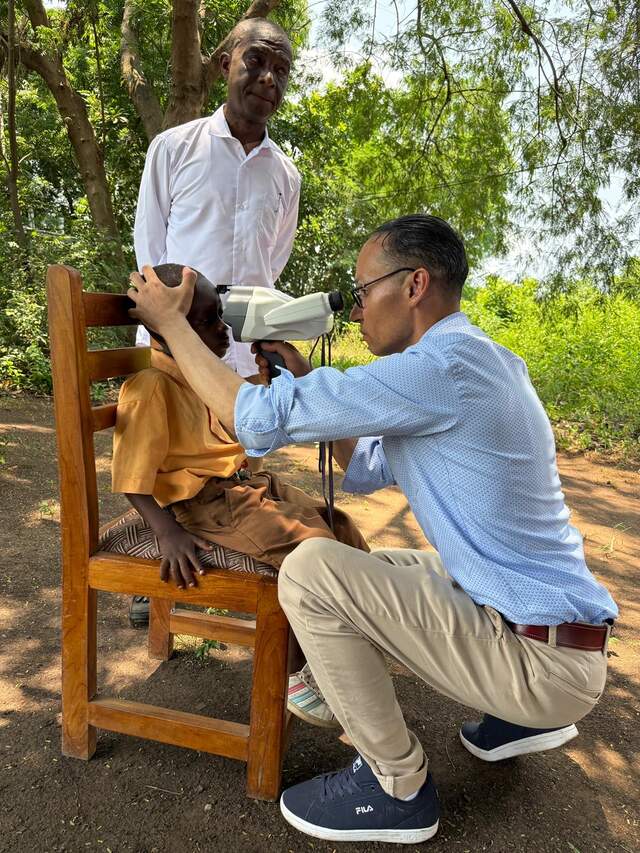 Opticien doet een oogmeting bij een kind uit Ghana